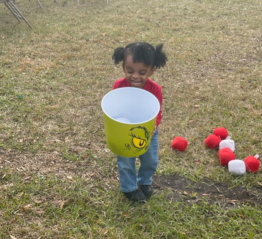 little girl holding the grinch trash can 